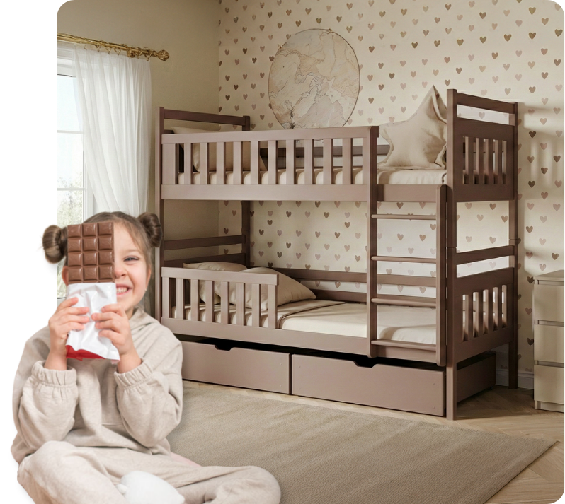 O fetiță zâmbitoare stă cu ciocolată pe fundalul unui pat supraetajat de culoarea ciocolatei